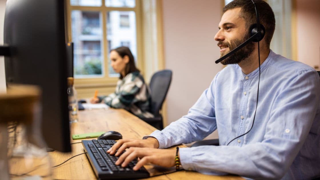 A salesman in the office with a headset consulting a client.