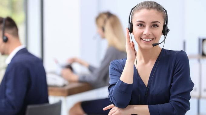 Smiling businesswoman with a headset, showcasing the evolution to Cloud PBX and SIP trunk telephony.